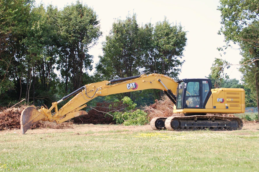 Excavator parked on grass near trees and brush