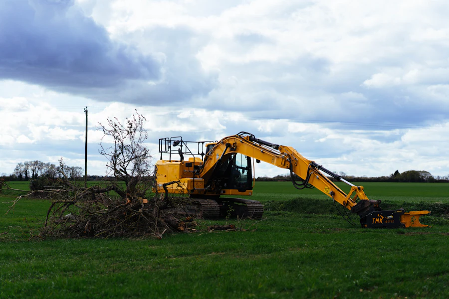 Excavator clearing branches and brush in a grassy field